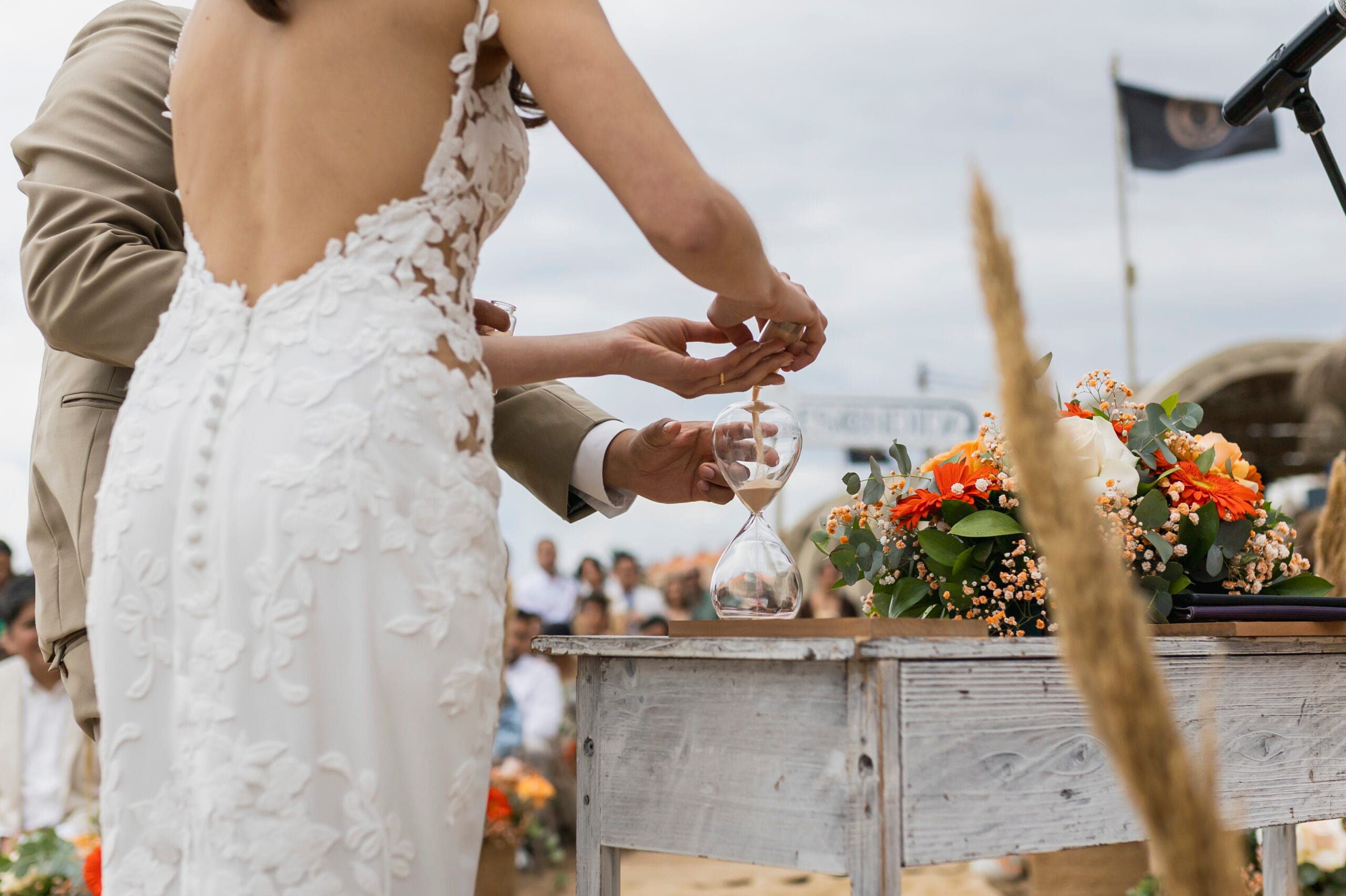 Novios realizando la ceremonia o ritual de la arena en un altar decorado con flores durante una boda al aire libre en Restaurante Escondida.